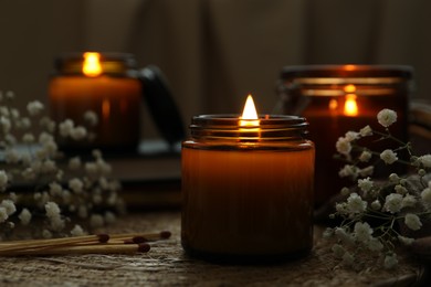 Burning candles and beautiful flowers on table