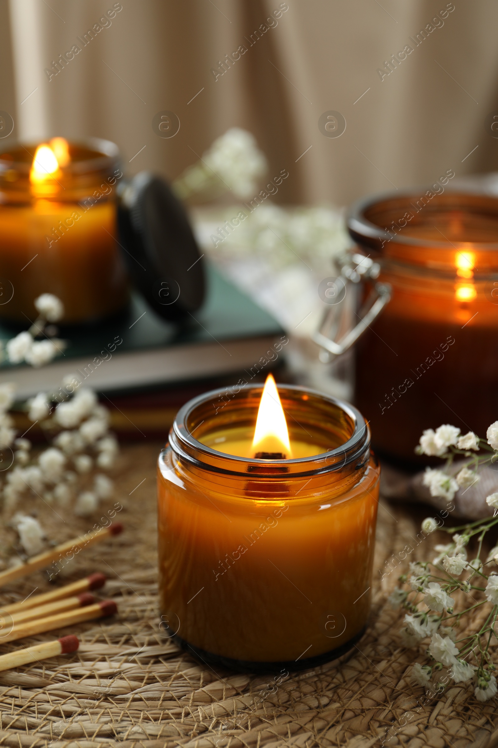 Photo of Burning candles and beautiful flowers on table