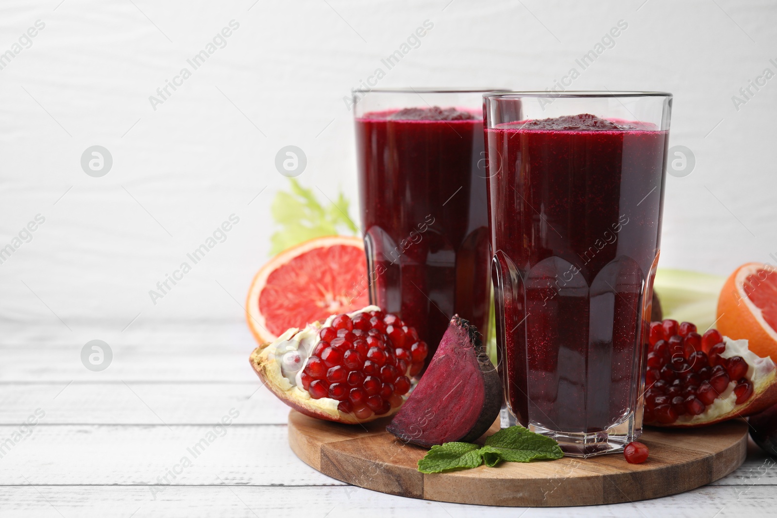 Photo of Fresh beetroot smoothie in glasses, grapefruit, beet and pomegranate on white wooden table. Space for text