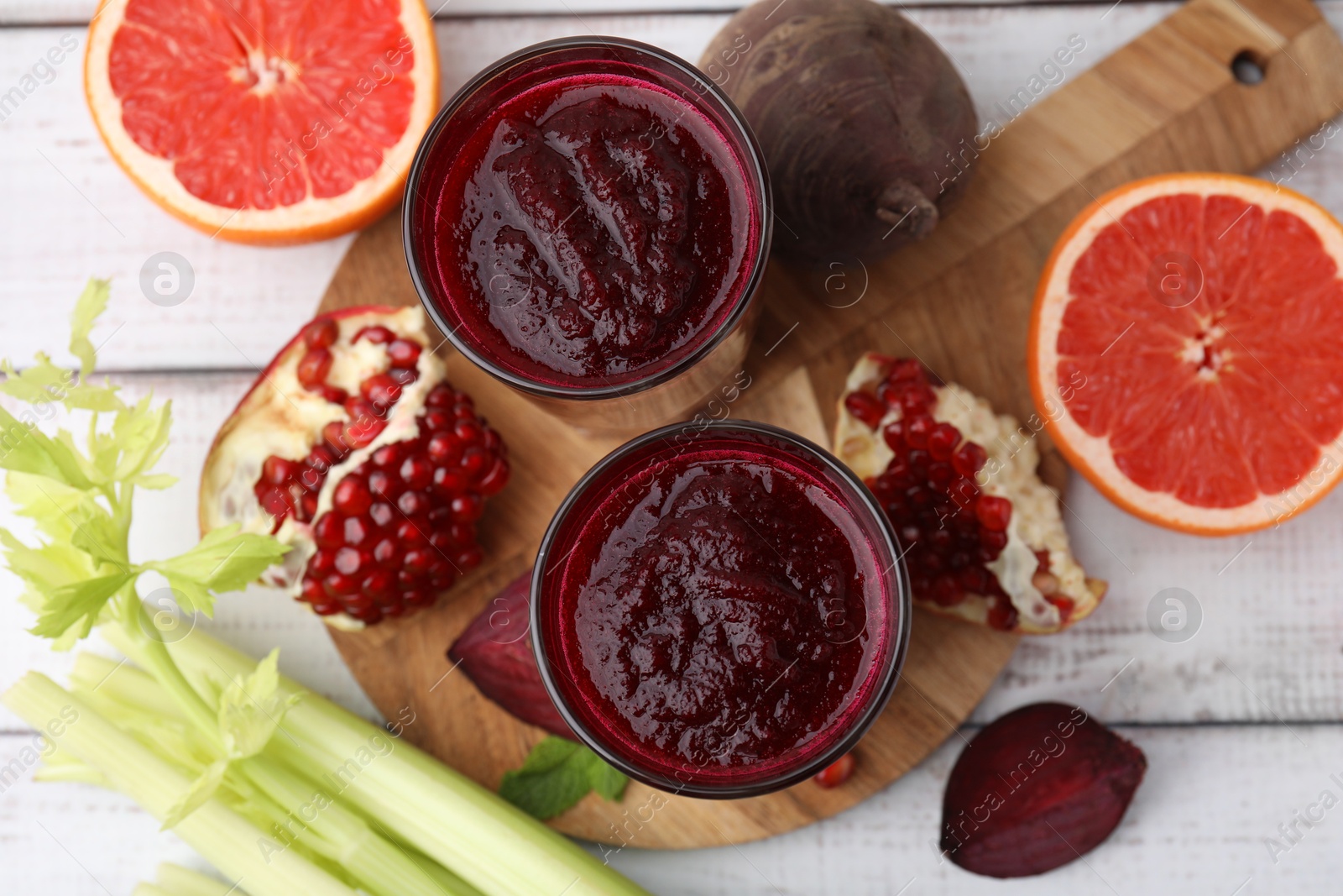 Photo of Fresh beetroot smoothie in glasses, grapefruit, beet and pomegranate on white wooden table, flat lay