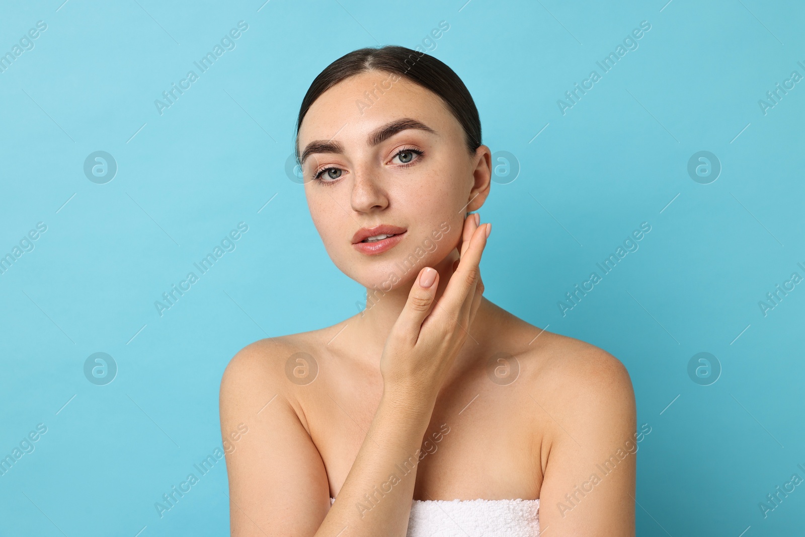 Photo of Face massage. Beautiful young woman with healthy skin on light blue background