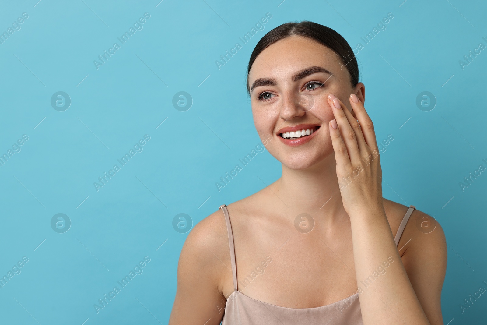 Photo of Face massage. Beautiful young woman with healthy skin on light blue background, space for text