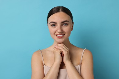 Beautiful young woman with healthy skin on light blue background