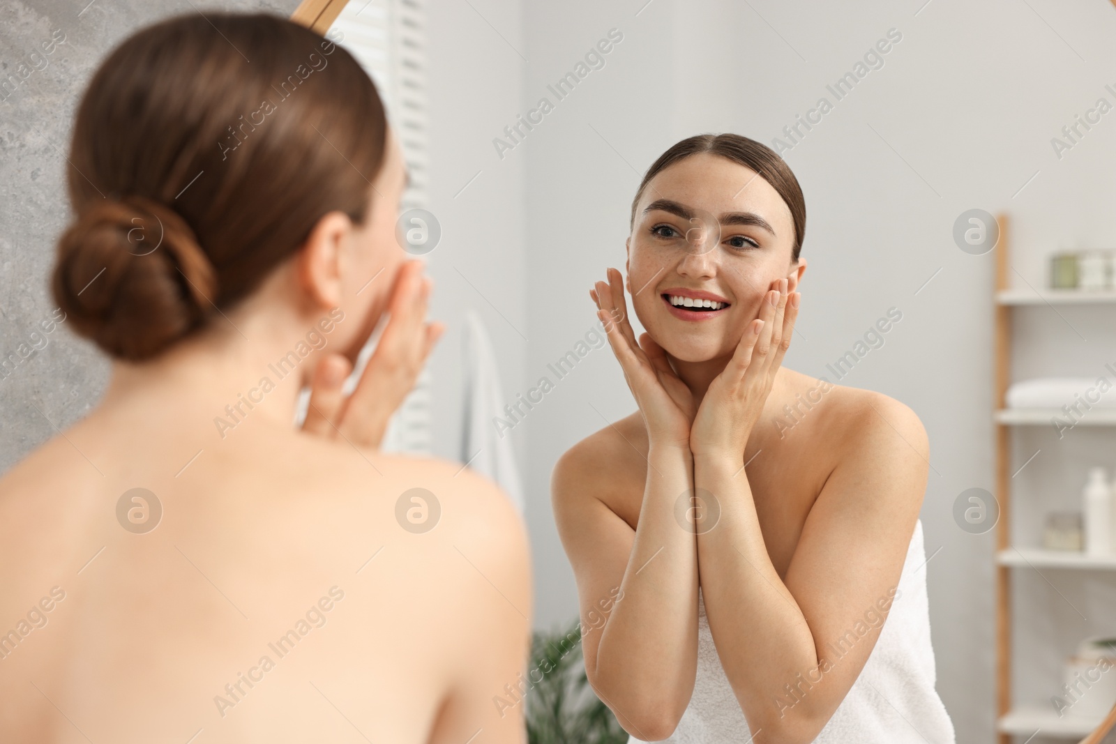 Photo of Face massage. Beautiful young woman with healthy skin near mirror at home