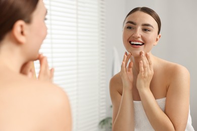 Face massage. Beautiful young woman with healthy skin near mirror at home