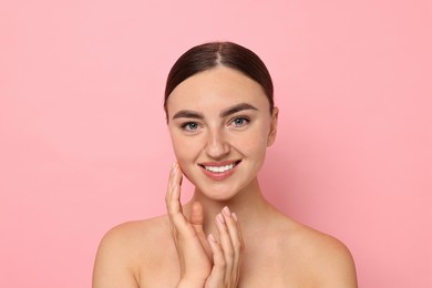 Beautiful young woman with healthy skin on pink background