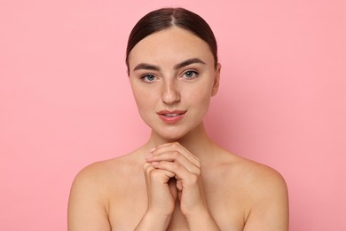 Beautiful young woman with healthy skin on pink background