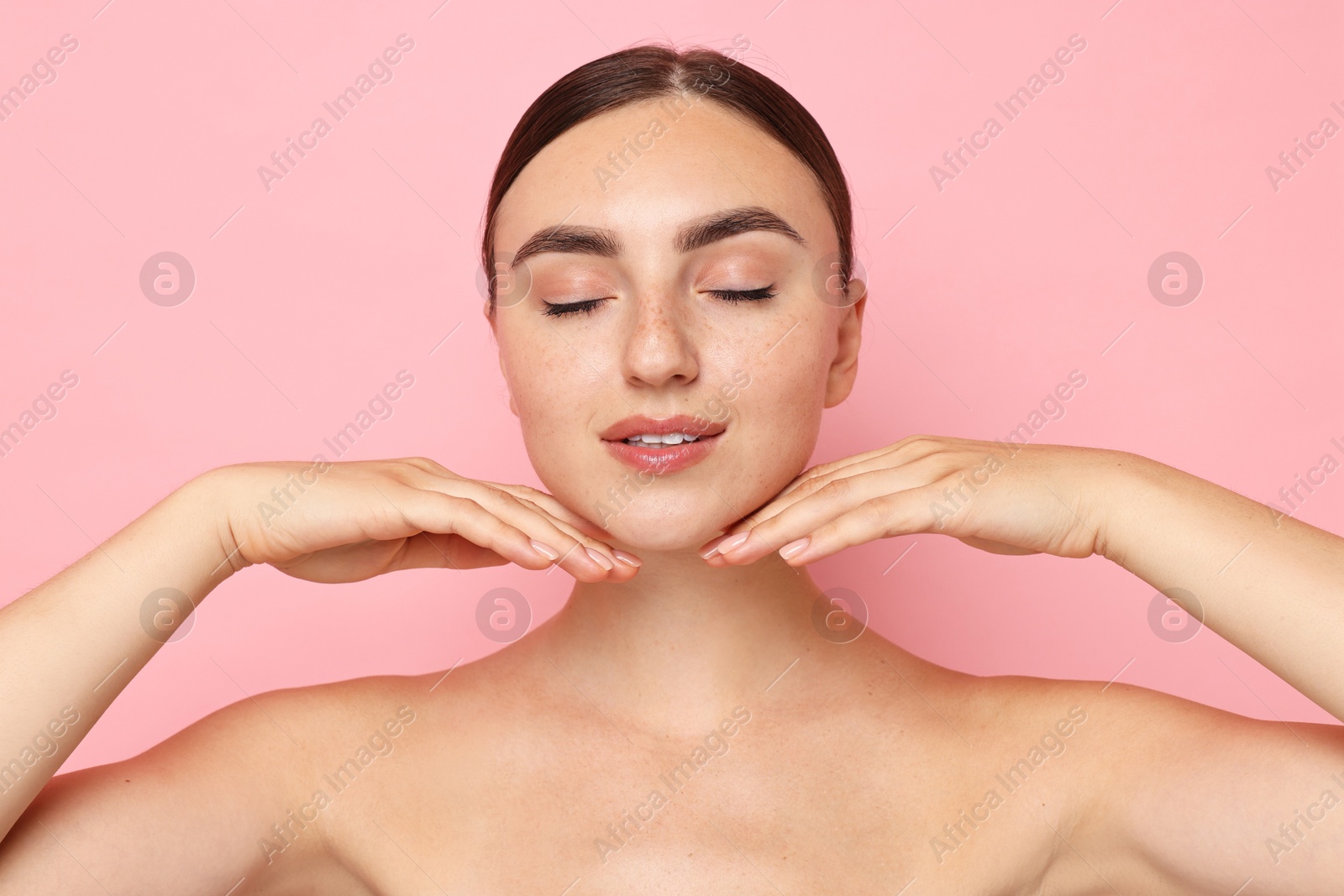 Photo of Face massage. Beautiful young woman with healthy skin on pink background