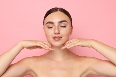 Face massage. Beautiful young woman with healthy skin on pink background