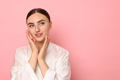 Face massage. Beautiful young woman with healthy skin on pink background, space for text