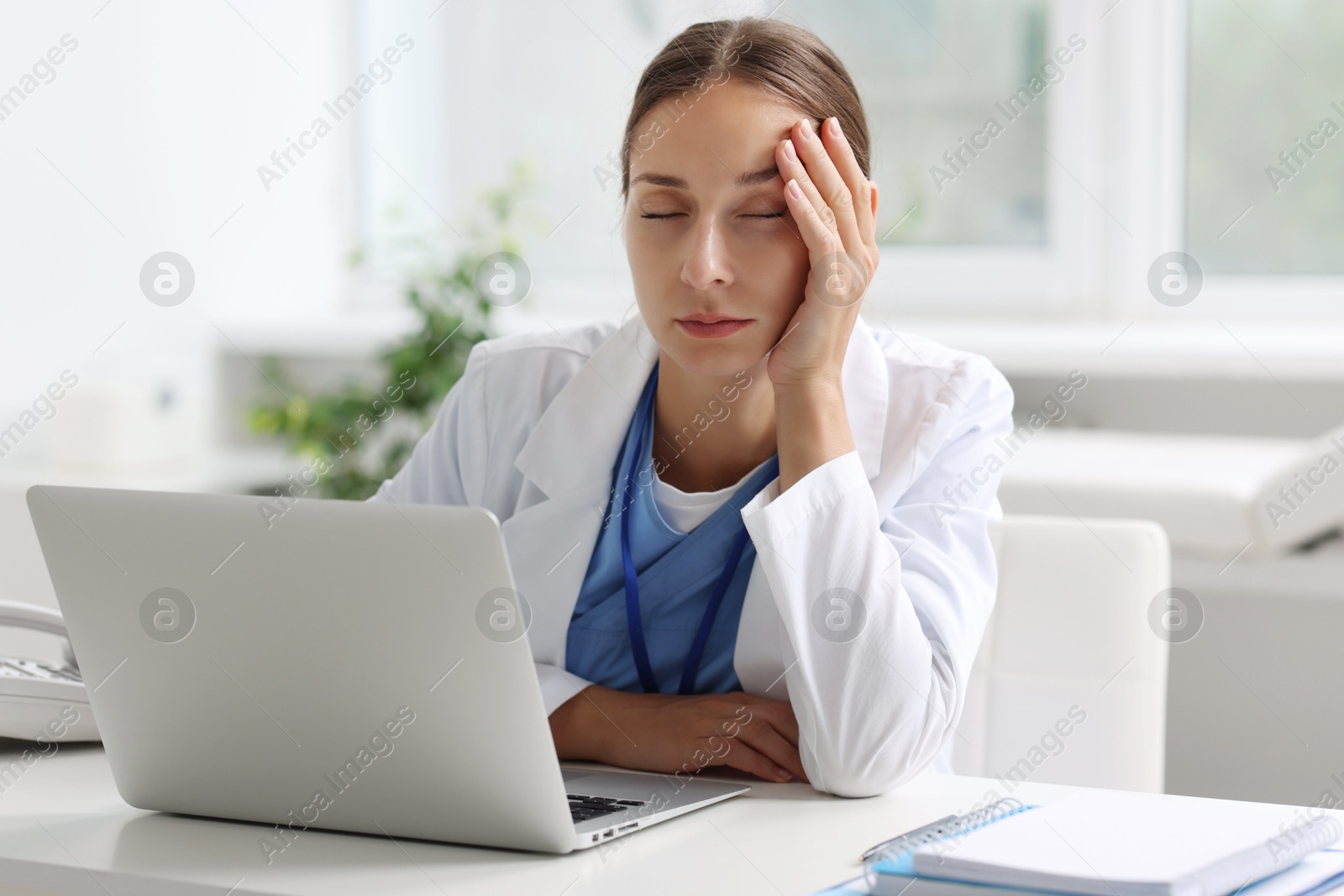 Photo of Tired nurse sleeping at white table in clinic