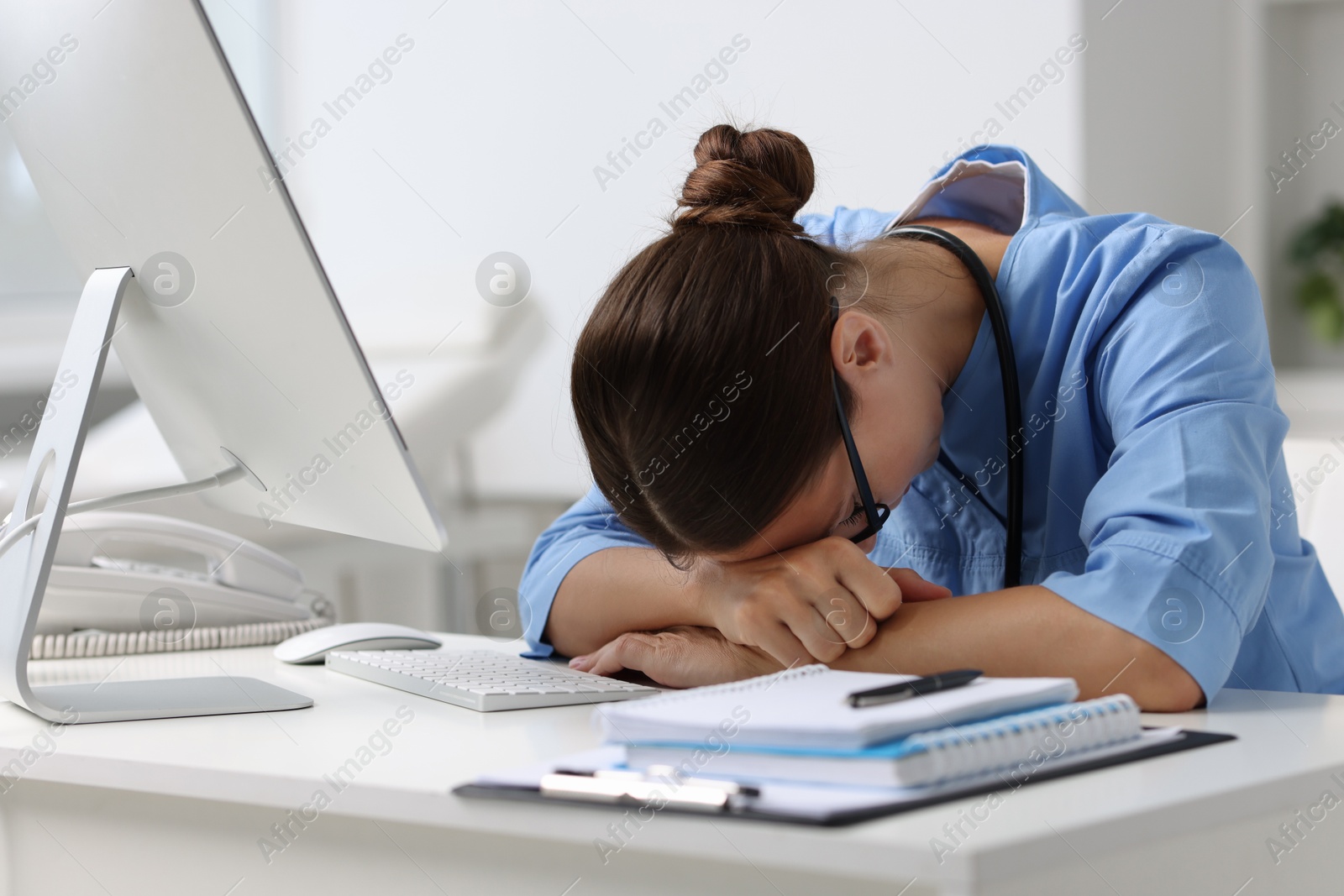 Photo of Tired nurse at white table in clinic