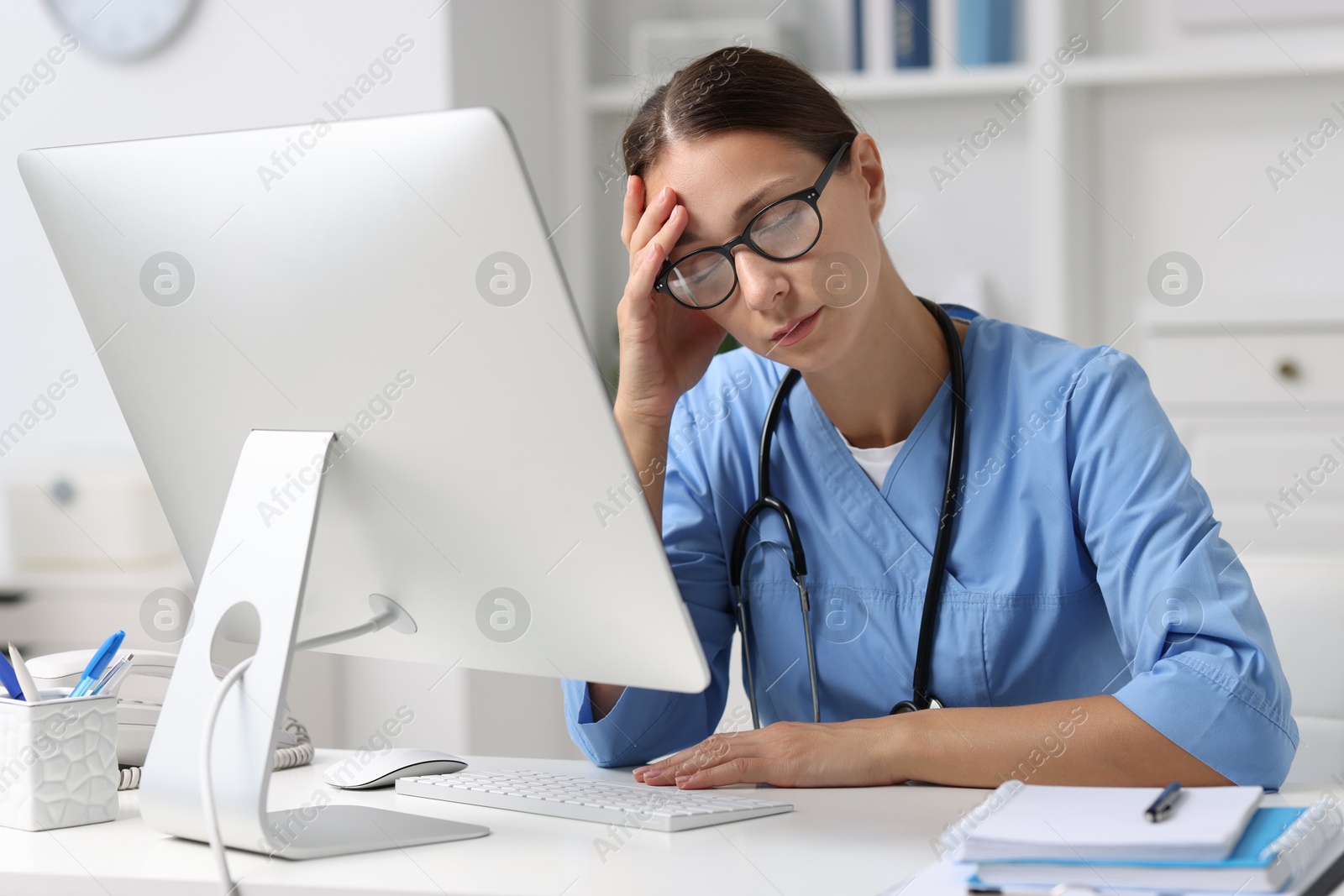 Photo of Tired nurse at white table in clinic