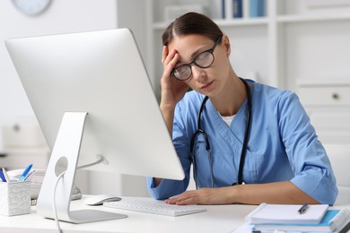 Photo of Tired nurse at white table in clinic