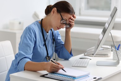 Tired nurse at white table in clinic