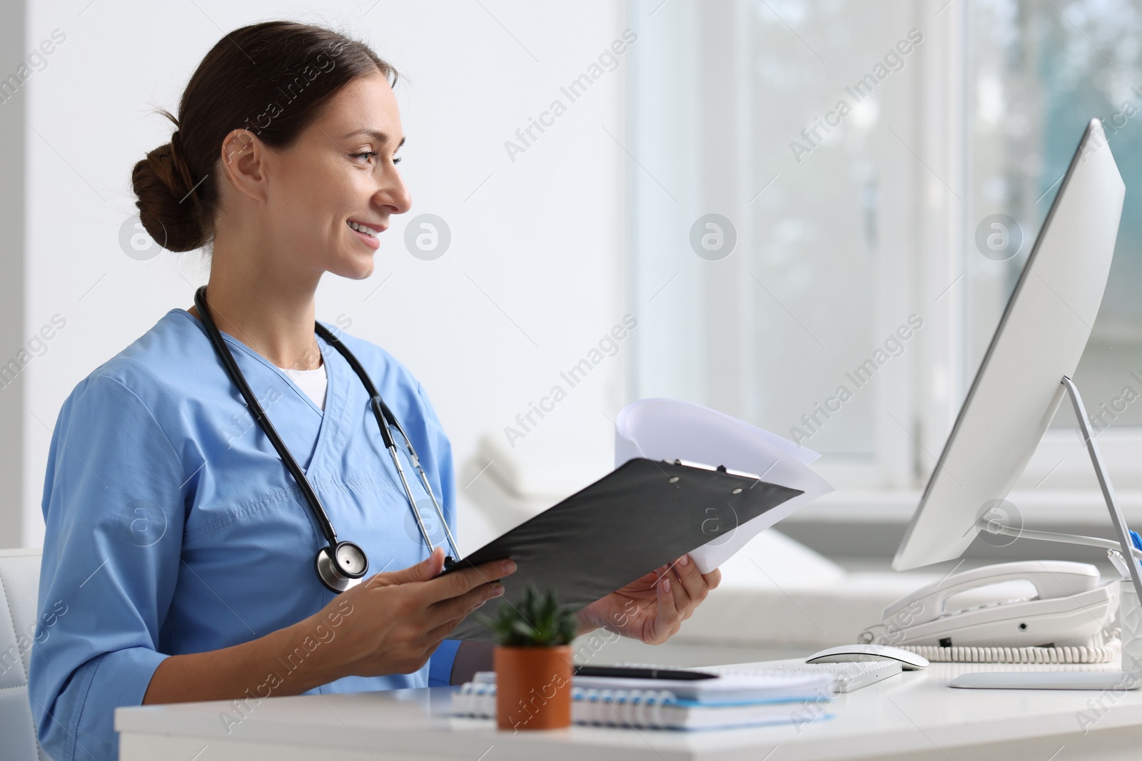 Photo of Nurse with clipboard at white table in clinic