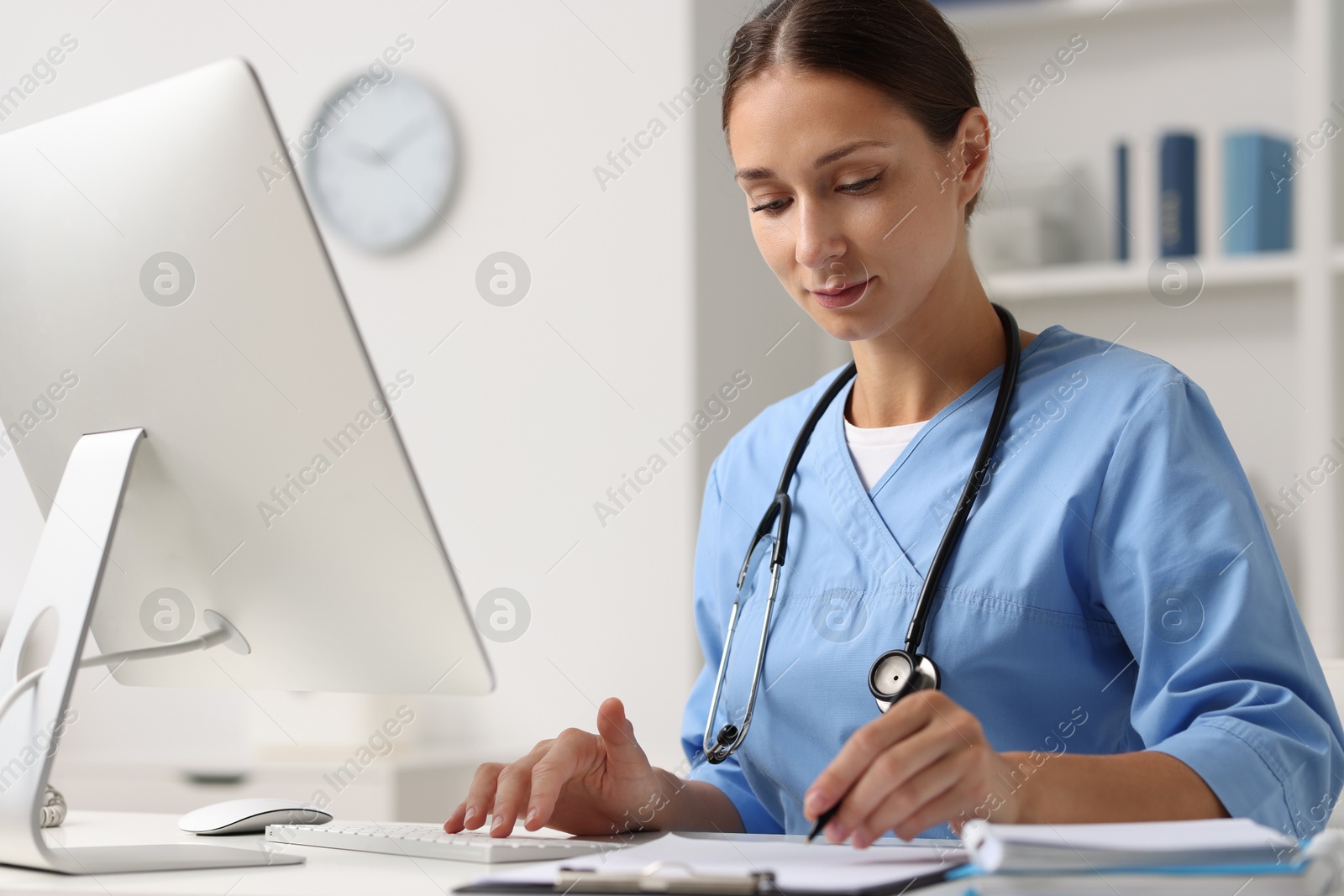 Photo of Nurse working on computer at table in clinic