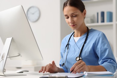 Nurse working on computer at table in clinic