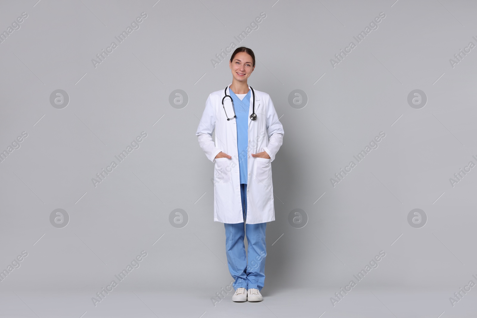 Photo of Nurse in medical uniform with stethoscope on grey background