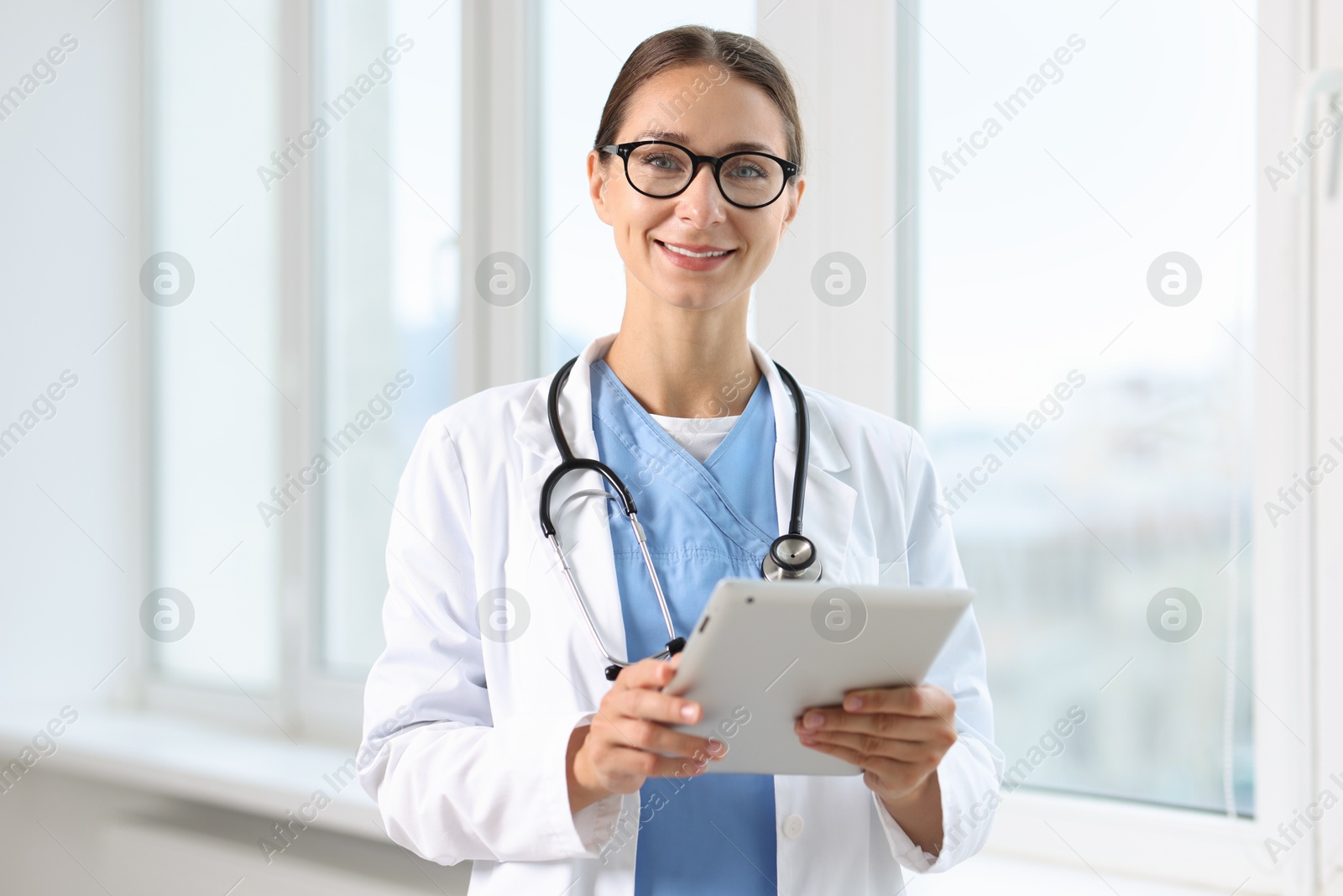 Photo of Nurse with stethoscope using tablet near window in clinic