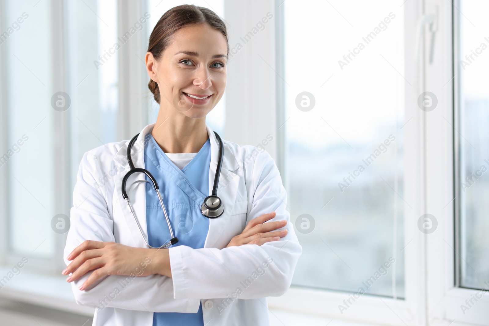 Photo of Nurse in medical uniform with stethoscope near window indoors