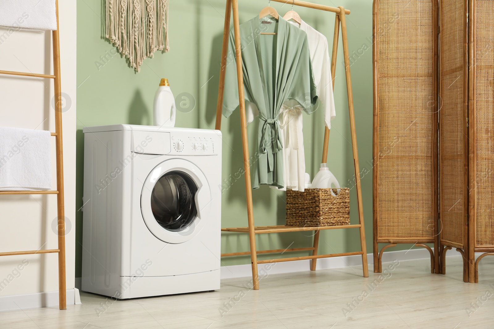 Photo of Washing machine, towels and detergent in laundry room