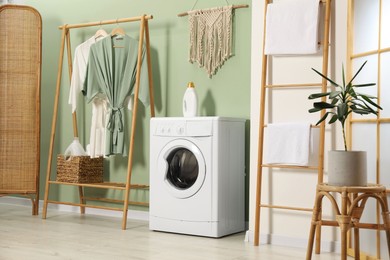 Photo of Washing machine, towels and detergent in laundry room