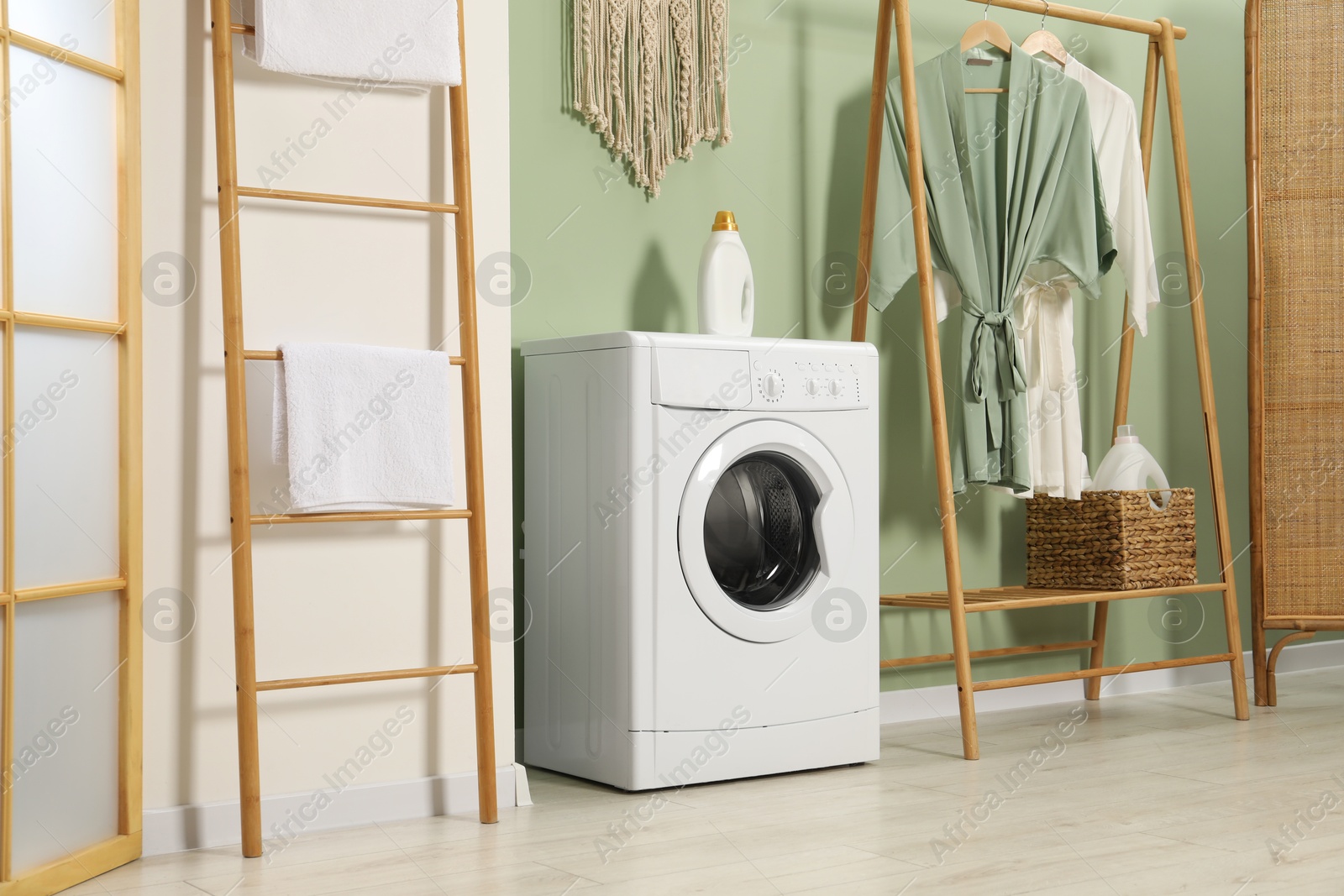 Photo of Washing machine, towels and detergent in laundry room