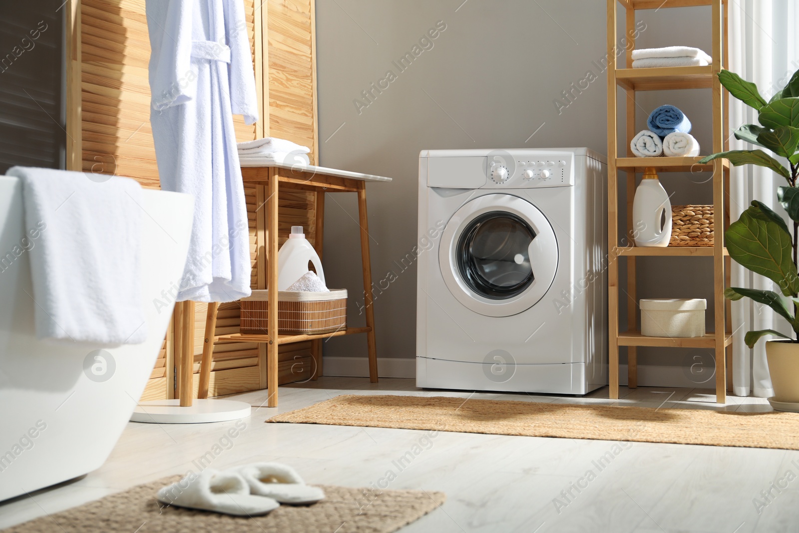 Photo of Washing machine, towels and detergents in bathroom