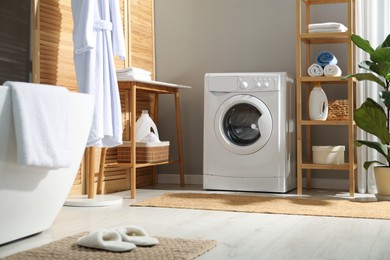 Photo of Washing machine, towels and detergents in bathroom