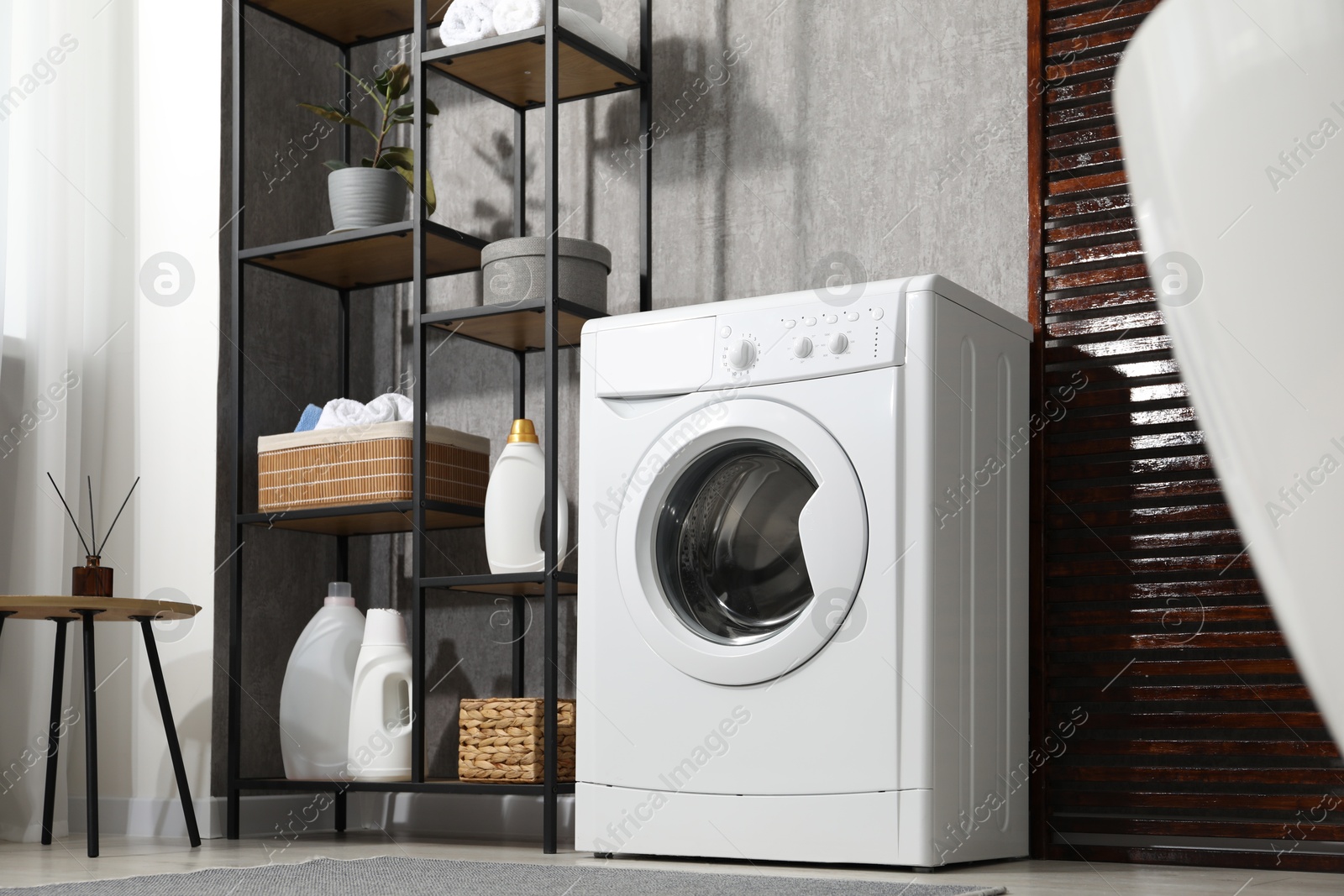 Photo of Washing machine and detergents in laundry room, low angle view