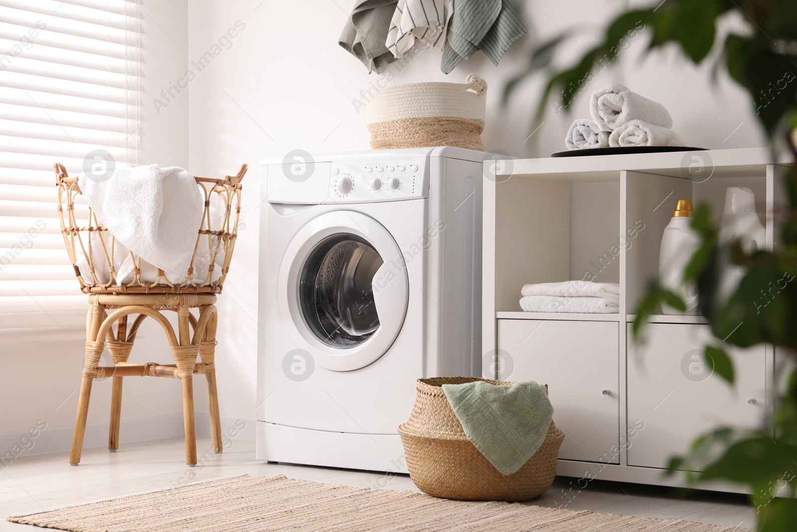 Photo of Washing machine, towels and detergents in laundry room