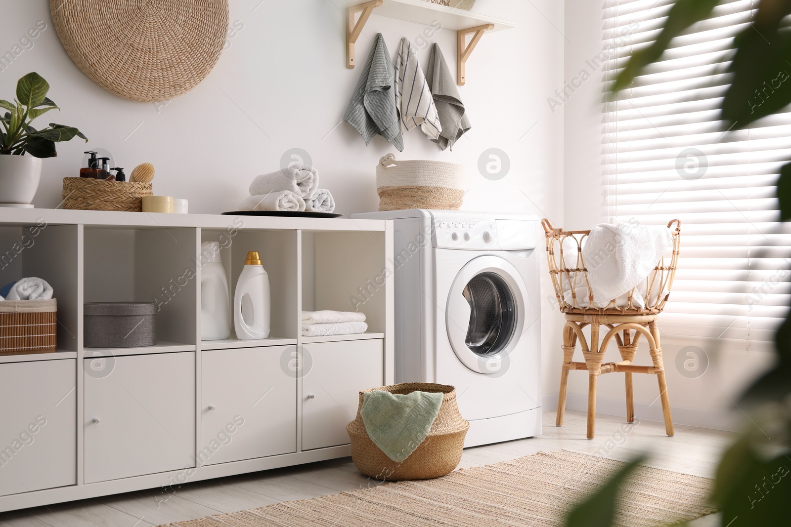 Photo of Washing machine, towels and detergents in laundry room