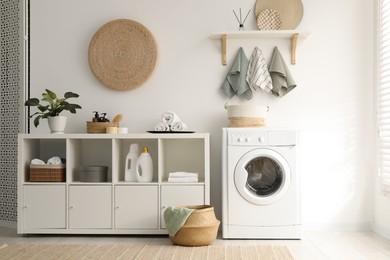 Photo of Washing machine, towels and detergents in laundry room