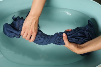 Woman washing denim clothes in basin, top view