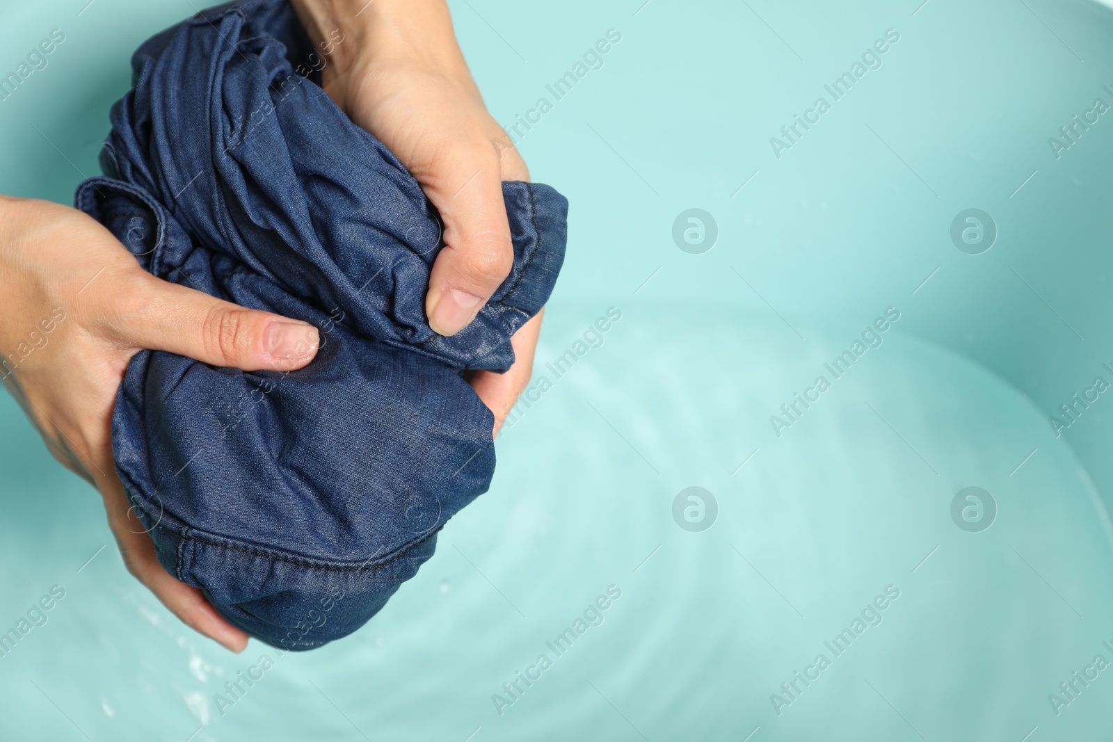 Photo of Woman washing denim clothes in basin, closeup. Space for text