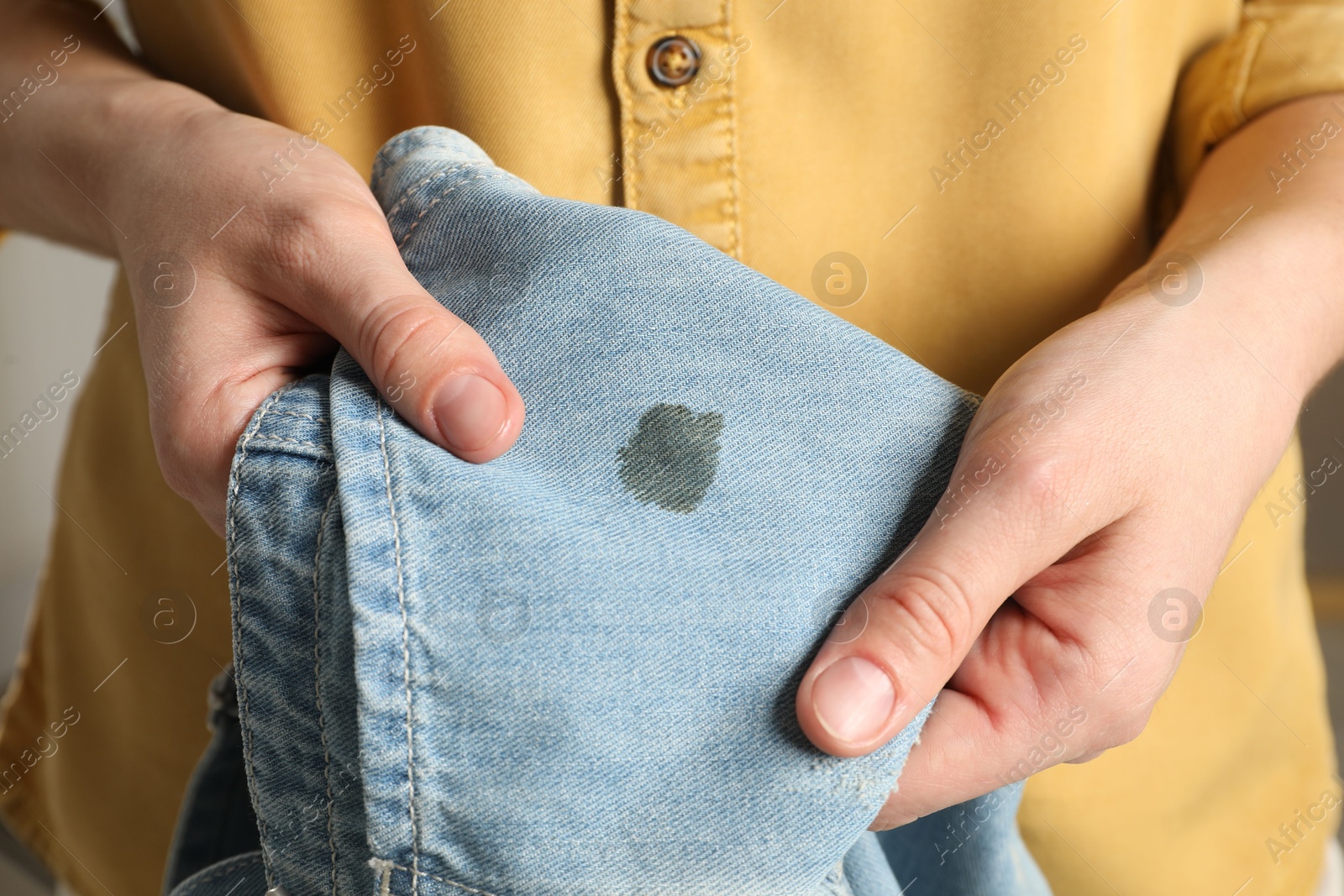 Photo of Washing clothes. Woman holding jeans with stain, closeup