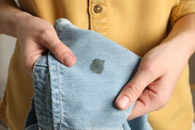 Photo of Washing clothes. Woman holding jeans with stain, closeup