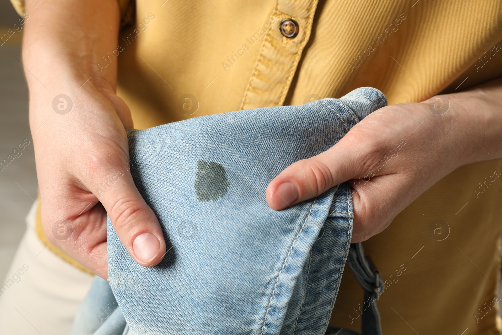 Photo of Washing clothes. Woman holding jeans with stain, closeup