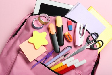 Photo of Backpack and different school stationery on pink background, top view