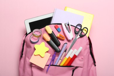 Photo of Backpack and different school stationery on pink background, top view