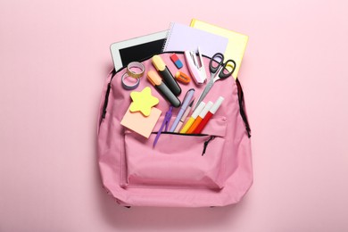 Photo of Backpack and different school stationery on pink background, top view