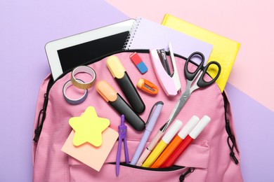 Photo of Backpack and different school stationery on color background, top view