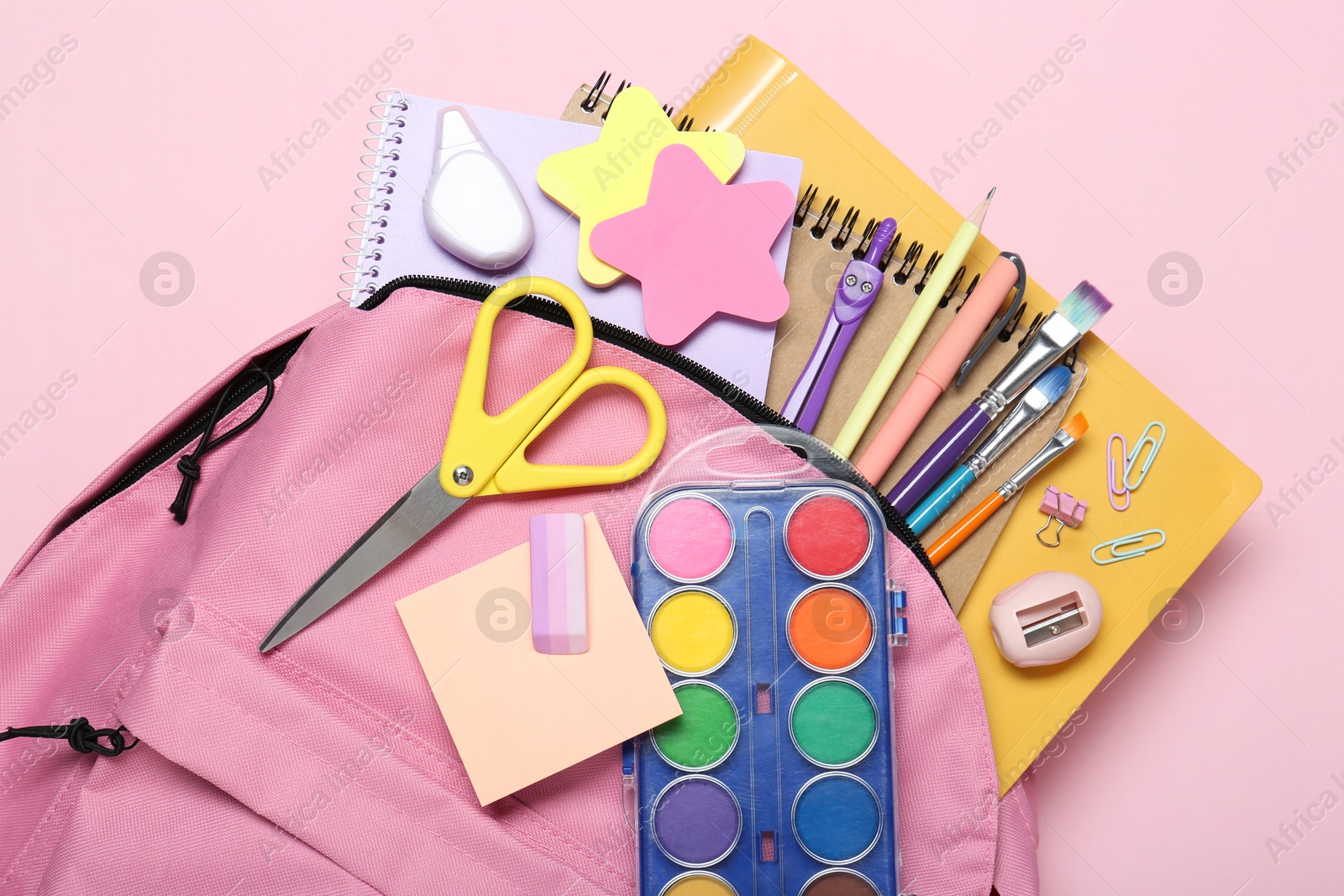 Photo of Backpack and different school stationery on pink background, top view