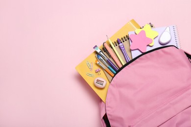 Photo of Backpack and different school stationery on pink background, top view. Space for text