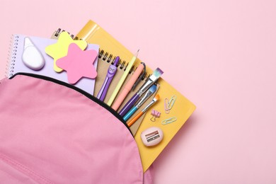 Photo of Backpack and different school stationery on pink background, top view. Space for text