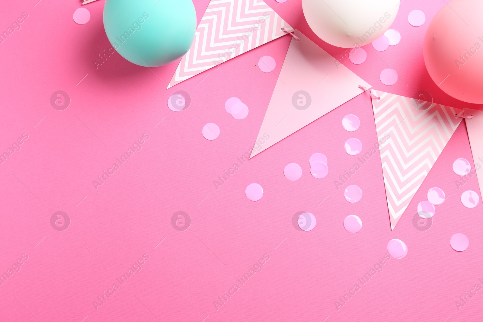 Photo of Confetti, garland and air balloons on pink background, flat lay. Space for text