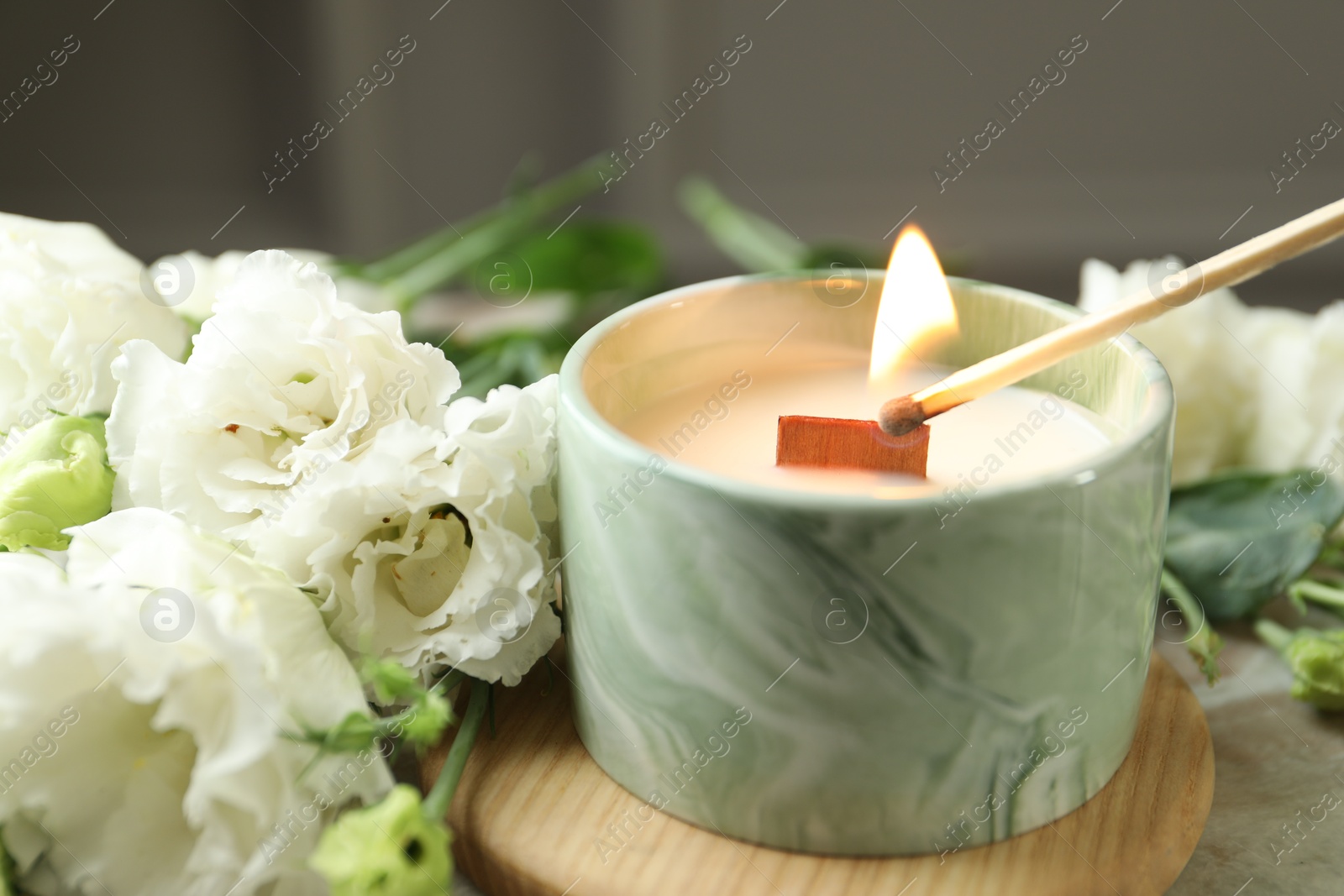 Photo of Lighting candle at table with beautiful flowers, closeup