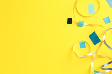 Photo of Beautiful confetti and party streamers on yellow background, flat lay. Space for text