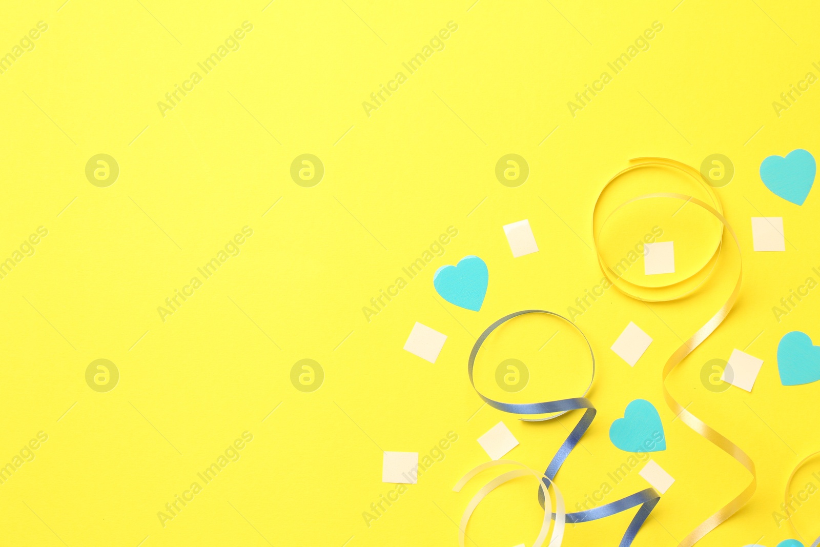 Photo of Beautiful confetti and party streamers on yellow background, flat lay. Space for text